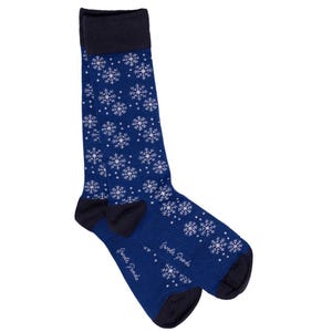 May include: A pair of blue socks with a white snowflake pattern. The socks have a navy blue cuff and the words "Fred's Pants" are written on the bottom of the socks.