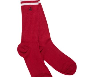 May include: A pair of red socks with white stripes at the top. The socks have a ribbed texture and a small black embroidered logo near the top. These socks are a classic athletic style.