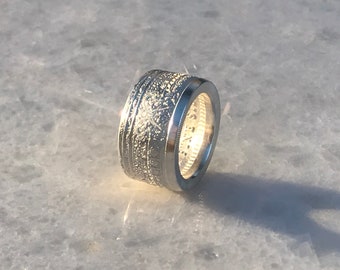 May include: Silver ring made from a coin with a textured design.