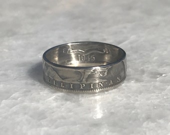 May include: A silver ring made from a 1945 Philippine coin. The ring features the inscription "PILIPINAS" and a depiction of a bird in flight.