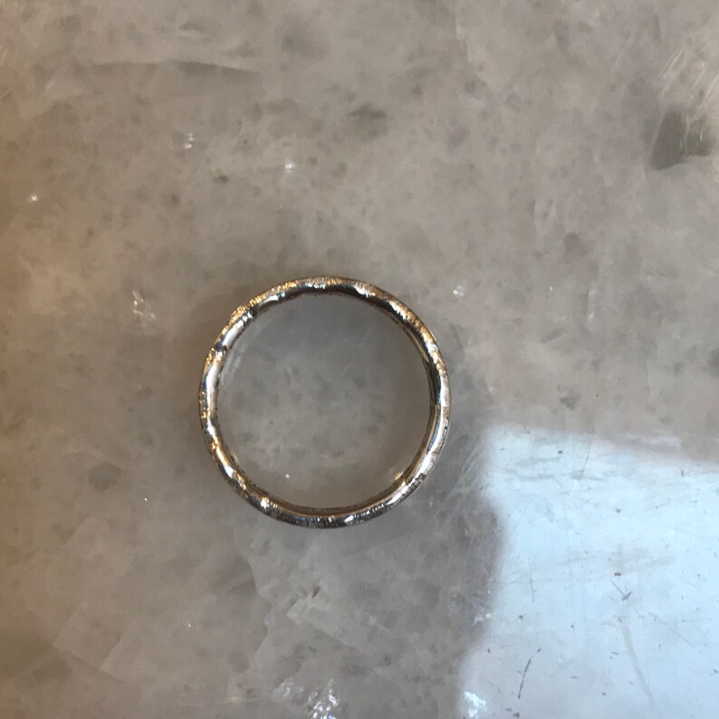 May include: A silver ring with a textured surface.
