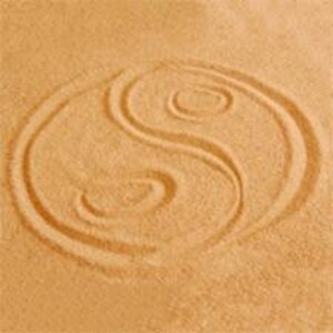May include: A close-up of a Yin and Yang symbol raked into sand. The symbol is a light brown colour, with a curved line dividing the circle into two halves. Each half contains a smaller circle.