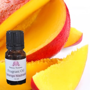 May include: A 10 ml bottle of mango scented essential oil with the label "Natures Treasures Fragrant Oil Mango Madness". The bottle is in front of slices of ripe mango fruit.