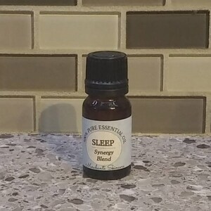 May include: A small brown glass bottle with a black cap. The bottle is labelled "100% Pure Essential Oil Sleep Synergy Blend Merchants Skincare".