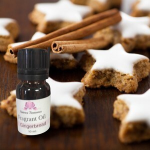 Peut inclure: Une petite bouteille en verre brun avec un bouchon noir et une étiquette blanche qui indique "Natures Treasures Fragrant Oil Gingerbread 10 ml". La bouteille est posée sur une surface en bois avec des biscuits en forme d'étoile et des bâtonnets de cannelle.