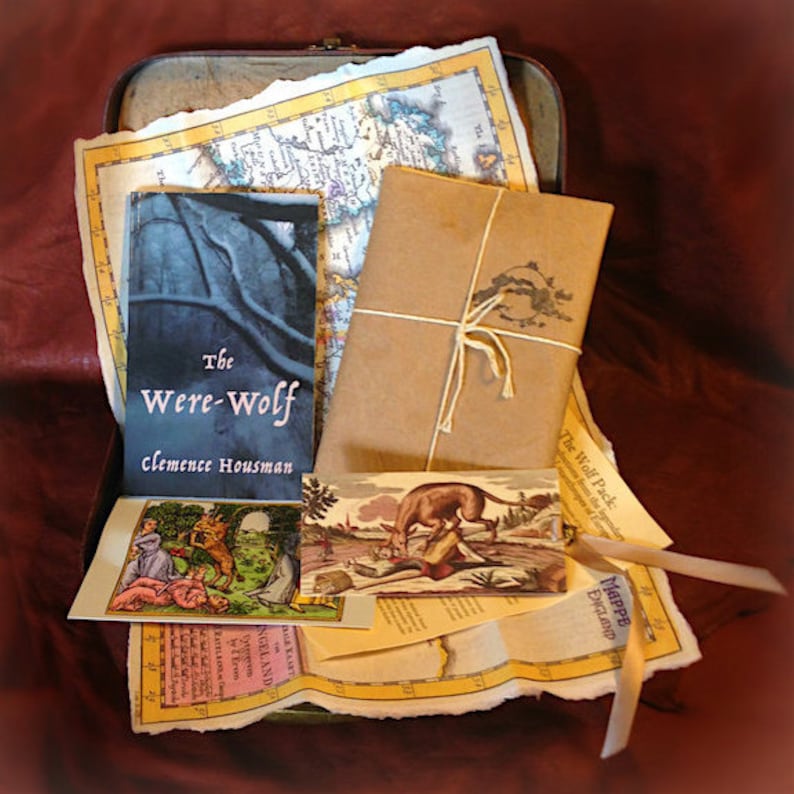 May include: An antique-style metal box with a worn, brown leather exterior. The box is open and contains a variety of items, including a book titled "The Were-Wolf" by Clemence Housman, a brown paper package tied with twine, a map of England, and a vintage illustration of a wolf.