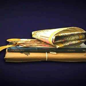 May include: A stack of books wrapped in brown paper with a yellow ribbon and a map in a fabric cover. The top book is titled "The Well-Well" and the second book is titled "Housman".
