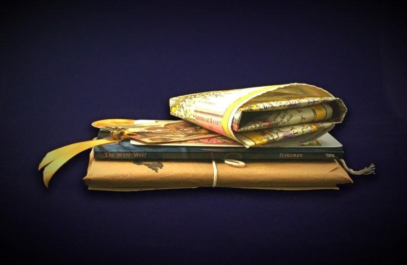 May include: A stack of books wrapped in brown paper with a yellow ribbon and a map in a fabric cover. The top book is titled "The Well-Well" and the second book is titled "Housman".