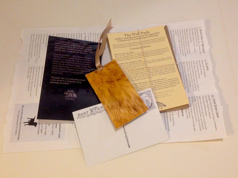 May include: A set of vintage postcards featuring a wolf pack, a fox, and a dog. The postcards are printed on thick paper with a textured surface. The text on the postcards reads "The Wolf Pack" and "The Fox".