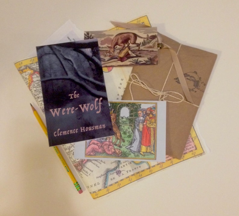 May include: A brown paper envelope with a string tied around it. The envelope is on top of a map with a book titled "The Were-Wolf" by Clemence Housman. There is a small card with a picture of a wolf and people in a forest.