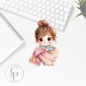 Peut inclure: Un autocollant représentant une fillette de dessin animé enveloppée dans une couverture à carreaux rose et blanche. La fille a les cheveux bruns en chignon et de grands yeux bleus. L'autocollant porte le texte "CREATION ET PAPETERIE" et un logo.