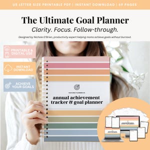 May include: A spiral-bound goal planner with a colorful striped cover. The planner includes the text "The Ultimate Goal Planner" and "annual achievement tracker & goal planner." The image also includes digital mockups of the planner.