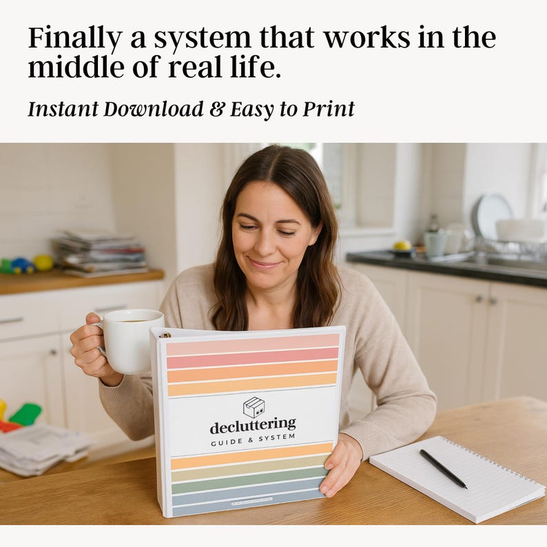 Mom sitting at kitchen table with coffee, reading printable decluttering guide and system binder in a real-life home setting with background clutter and notebook beside her