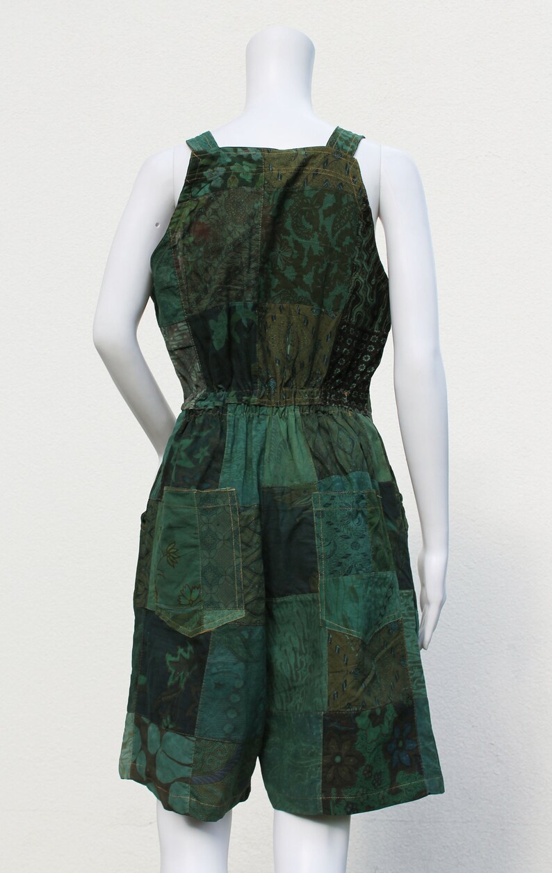 May include: A green patchwork jumpsuit with a halter neckline and a drawstring waist. The jumpsuit is made of different fabrics with floral and paisley patterns.