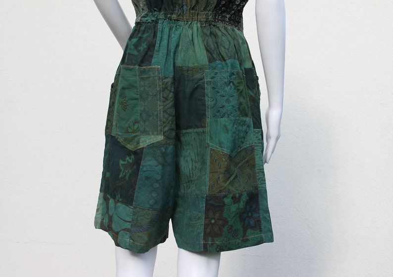 May include: Green patchwork shorts with a drawstring waist and pockets. The shorts are made of different fabrics with floral and geometric patterns.