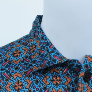 Könnte beinhalten: Ein Hemd mit Knopfleiste und einem Muster in Blau, Braun und Rosa.