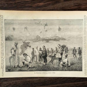 Op de afbeelding: Een vintage zwart-wit illustratie uit "The Boy's Own Paper" met een vliegerfestival in China. De afbeelding toont mensen die vliegers oplaten, waaronder een draakvormige vlieger, in de buurt van een water. De tekst "The Boy's Own Paper" is zichtbaar.