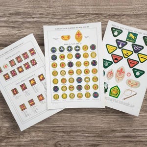 May include: Three sheets of paper with Boy Scout badges and insignia. The sheets display various merit badges and emblems in a variety of colors and shapes, including circles, triangles, and rectangular badges. The text on the sheets reads "Badges to be Earned by Boy Scouts."