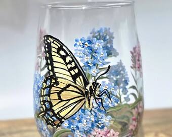 Bicchiere da vino senza stelo con farfalla coda di rondine dipinta a mano tra i fiori estivi: un regalo perfetto per gli amanti della natura.