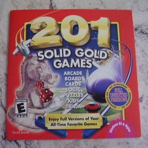 May include: A red game CD case with the title "201 Solid Gold Games" in gold lettering. The cover features a knight chess piece, dice, and various game-related graphics. The text includes "Arcade, Board, Cards, Logic, Puzzles, Kids, Trivia."