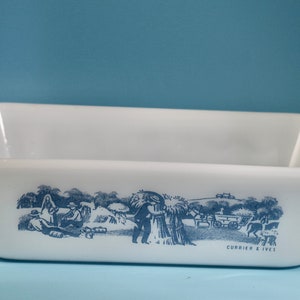May include: White ceramic loaf pan with a blue and white design of a rural scene with people and a horse-drawn wagon. The text "CURRIER & IVES" is printed on the bottom of the pan.