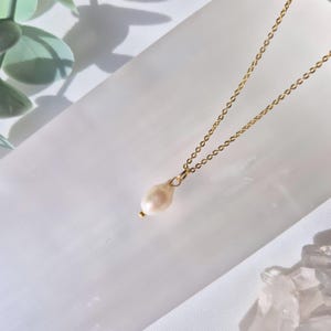 Dainty Real Pearl Necklace on an 18k gold plated chain resting on a selenite crystal bowl with floral and crystals in the background