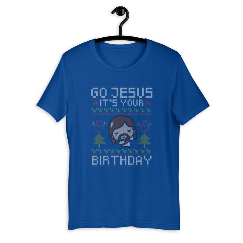 May include: Royal blue t-shirt with the text "GO JESUS IT'S YOUR BIRTHDAY" in a pixelated font. The design includes a cartoon Jesus, snowmen, and Christmas trees, creating a festive holiday theme.