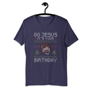 May include: Navy blue t-shirt with a graphic design. The design features the text "GO JESUS IT'S YOUR BIRTHDAY" in a pixelated font, along with an illustration of Jesus and Christmas trees.