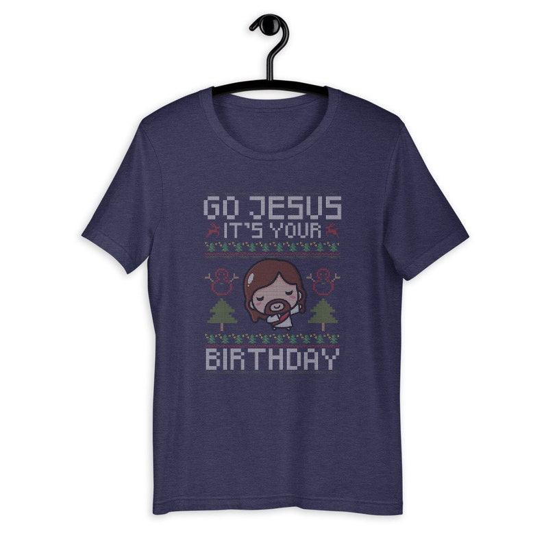May include: Navy blue t-shirt with a graphic design. The design features the text "GO JESUS IT'S YOUR BIRTHDAY" in a pixelated font, along with an illustration of Jesus and Christmas trees.