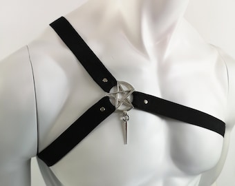 May include: Black adjustable harness with a silver pentagram pendant. The harness has two straps that cross in the front and attach to a metal ring with a pentagram charm.