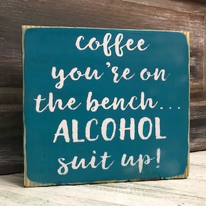 May include: Teal wooden sign with white text that reads "coffee you're on the bench... ALCOHOL sit up!"