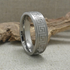 Op de afbeelding: Een zilveren titanium ring met een Grieks sleutelpatroon gegraveerd rond de band.