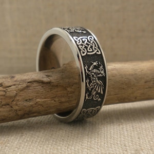 Op de afbeelding: Een zilveren ring met een zwart draak en Keltisch knoopontwerp.