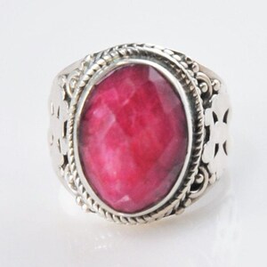 May include: A silver ring with an oval-shaped, pink gemstone set in a detailed, ornate silver setting.