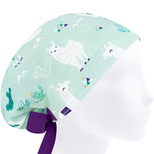 Peut inclure: Un bonnet de chirurgien vert clair avec un lien violet. Le bonnet est orné d'un motif de lamas blancs, de cactus et de formes géométriques.