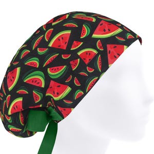Puede incluir: Un gorro quirúrgico negro con un estampado de rodajas de sandía rojas y cáscaras verdes. El gorro tiene una cinta verde. Diseñado para uso médico o profesional, está hecho de un material suave y cómodo.