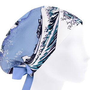 May include: A light blue surgical scrub cap with a wave and boat design in blue, teal, and white. The cap has a light blue tie closure at the back. The cap is designed for use in a medical environment.