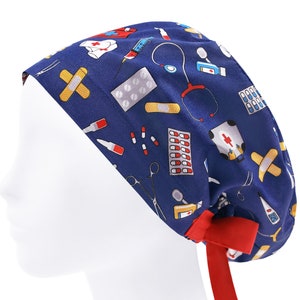 Peut inclure: Un bonnet de chirurgien bleu avec un ruban rouge. Le bonnet est imprim&eacute; avec divers symboles m&eacute;dicaux, notamment des pilules, des bandages, des seringues et des st&eacute;thoscopes.