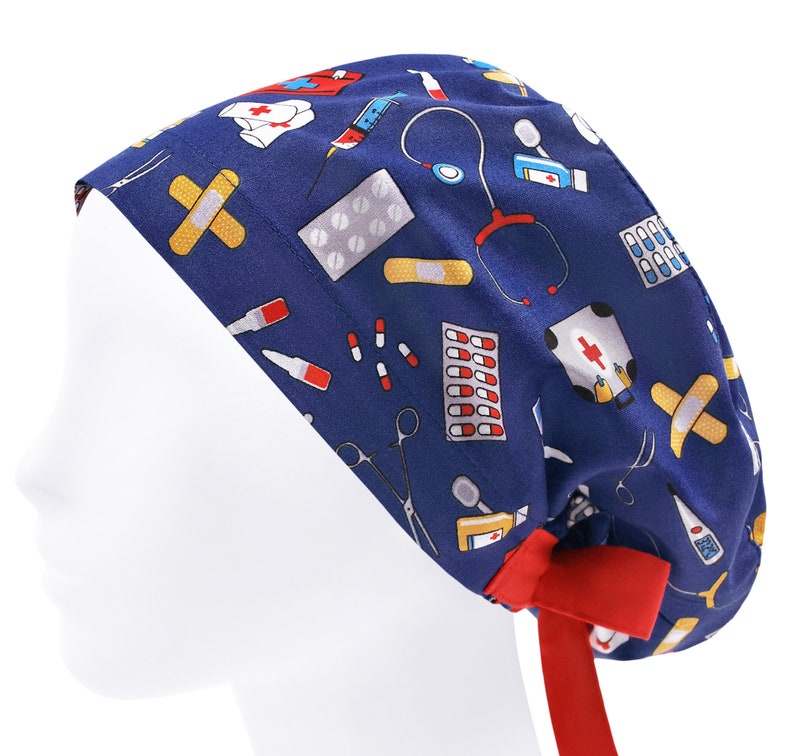 Peut inclure: Un bonnet de chirurgien bleu avec un ruban rouge. Le bonnet est imprim&eacute; avec divers symboles m&eacute;dicaux, notamment des pilules, des bandages, des seringues et des st&eacute;thoscopes.