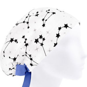 Könnte beinhalten: Eine weiße OP-Haube mit einem schwarzen Sternbild- und Sternenmuster, das durch dünne schwarze Linien verbunden ist. Die Haube verfügt über ein einfarbiges blaues Band am Hinterkopf, um den Stoff gerafft am Kopf zu fixieren.