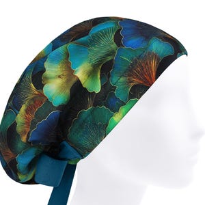 Può includere: Un cappello chirurgico fantasia con un design botanico di foglie di ginkgo verde acqua, verdi e dorate su sfondo nero. Il cappello ha un laccio verde acqua sul retro. Progettato per i professionisti medici.
