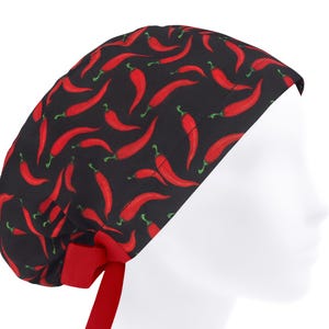 Puede incluir: Un gorro quirúrgico negro con un patrón repetido de chiles rojos. El gorro tiene una cinta roja en la parte posterior para un ajuste ajustable. Diseñado para profesionales médicos o cualquier persona que necesite protección para el cabello.