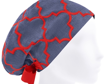May include: A scrub cap featuring a denim-blue fabric base with a vibrant red quatrefoil geometric pattern. The cap includes a matching red fabric tie at the back, designed to secure the fit around the head with a rounded, full-coverage shape.