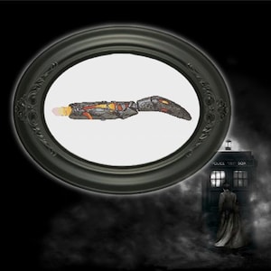 Peut inclure: Un tournevis sonique noir et orange, un outil fictif utilisé par le Docteur dans la série télévisée de science-fiction britannique Doctor Who, est présenté dans un cadre noir de forme ovale.