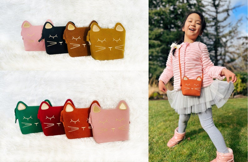 May include: Six different coloured cat-shaped purses with gold embroidery. The purses are lined up on a white fluffy surface. A young girl is wearing a pink sweater and a tulle skirt and is carrying a brown cat-shaped purse.