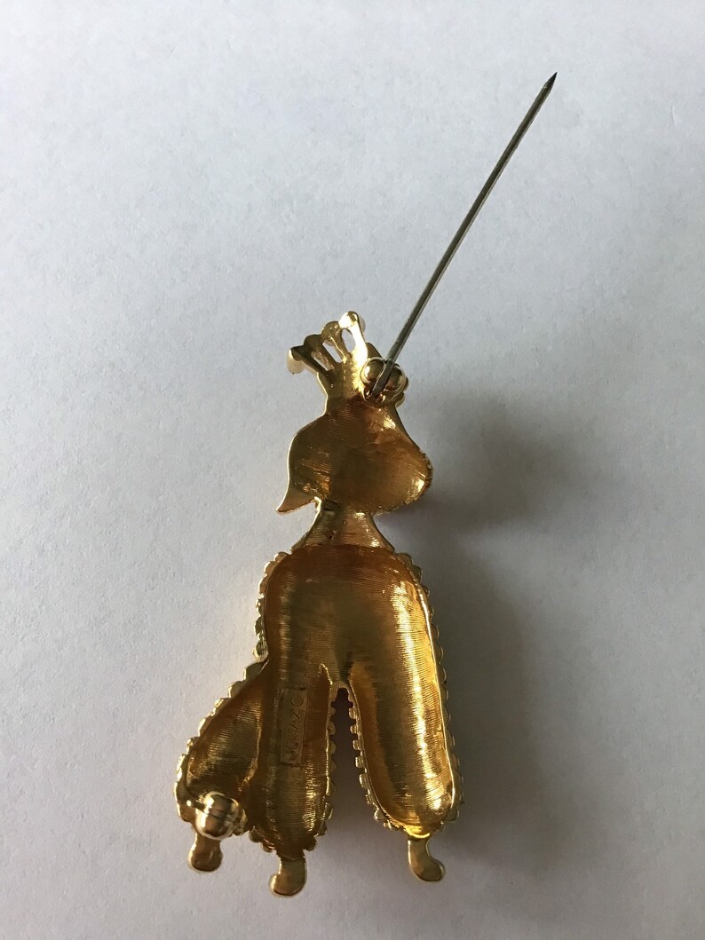 Designer signed Jomaz Goldtone poodle brooch wearing a crown and collar encrusted with crystal Textured metal fur detail.