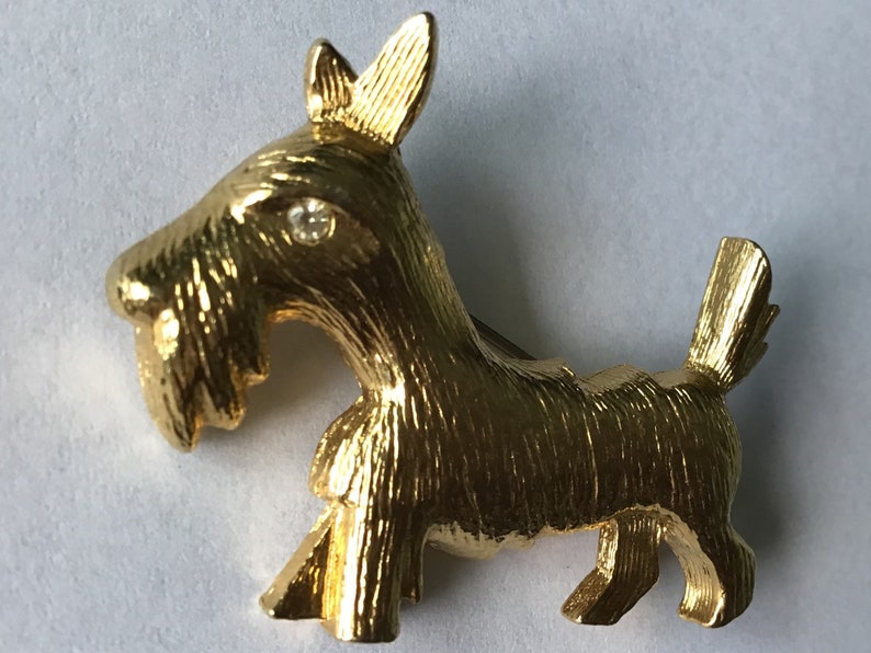 Designer signed Jomaz Goldtone poodle brooch wearing a crown and collar encrusted with crystal Textured metal fur detail.