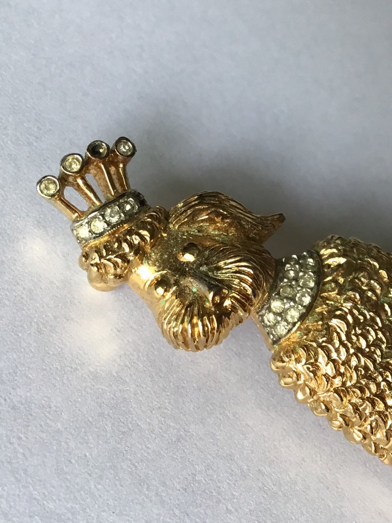 Designer signed Jomaz Goldtone poodle brooch wearing a crown and collar encrusted with crystal Textured metal fur detail.