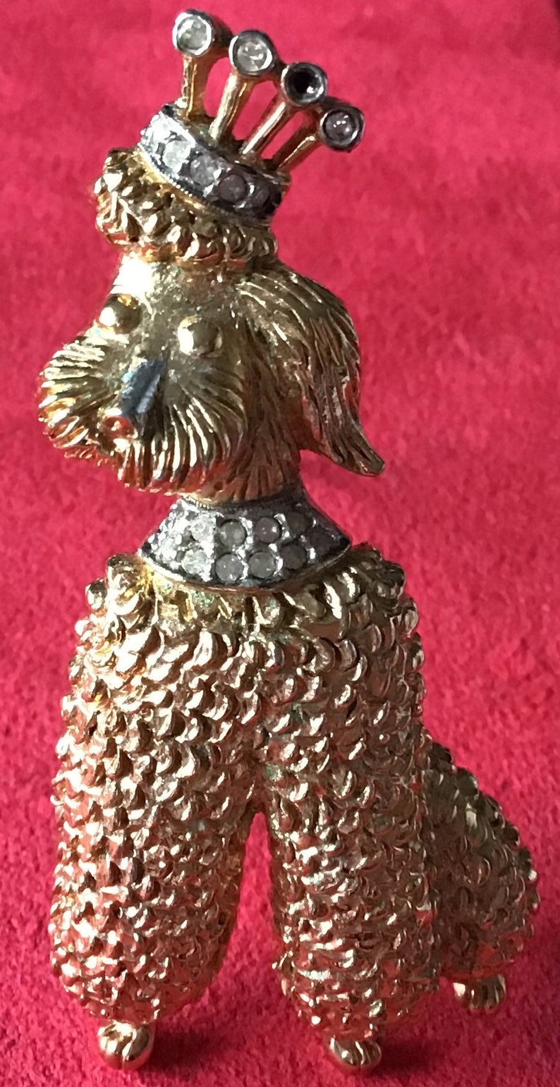 Designer signed Jomaz Goldtone poodle brooch wearing a crown and collar encrusted with crystal Textured metal fur detail.