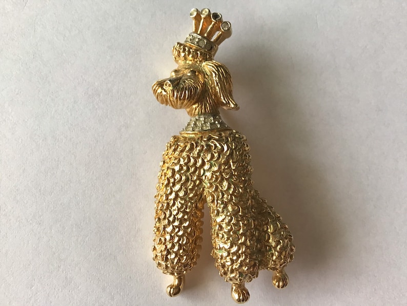 Designer signed Jomaz Goldtone poodle brooch wearing a crown and collar encrusted with crystal Textured metal fur detail.